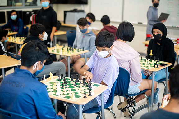 Students look intently at the chess board as they ponder their next moves.